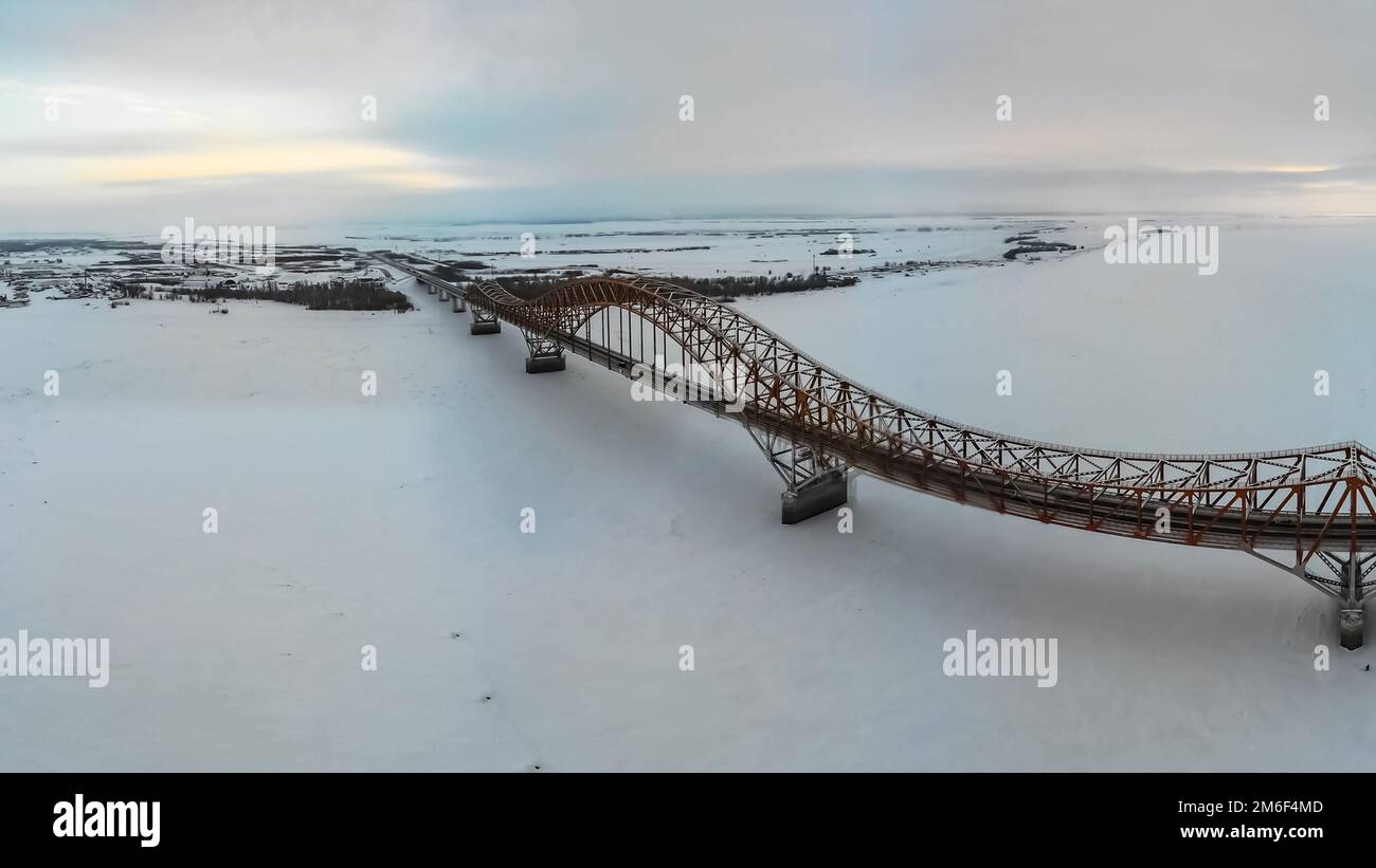 Brücke über den Fluss im Eis im Winter. Die Öl-Yugan-Brücke über die Region. Stockfoto