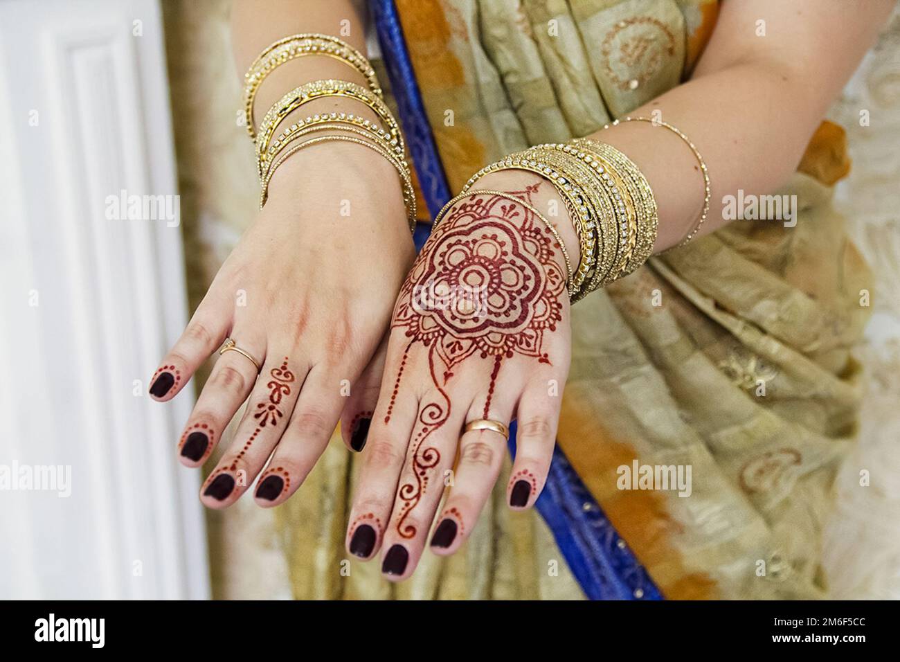 Indianerfrau trägt goldene Armbänder und Tattoos. Stockfoto