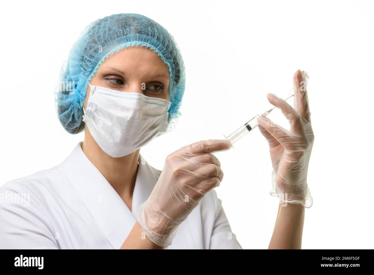 Krankenschwester in Maske und Handschuhe zieht Medizin mit einer Spritze Aus einer Ampulle Stockfoto