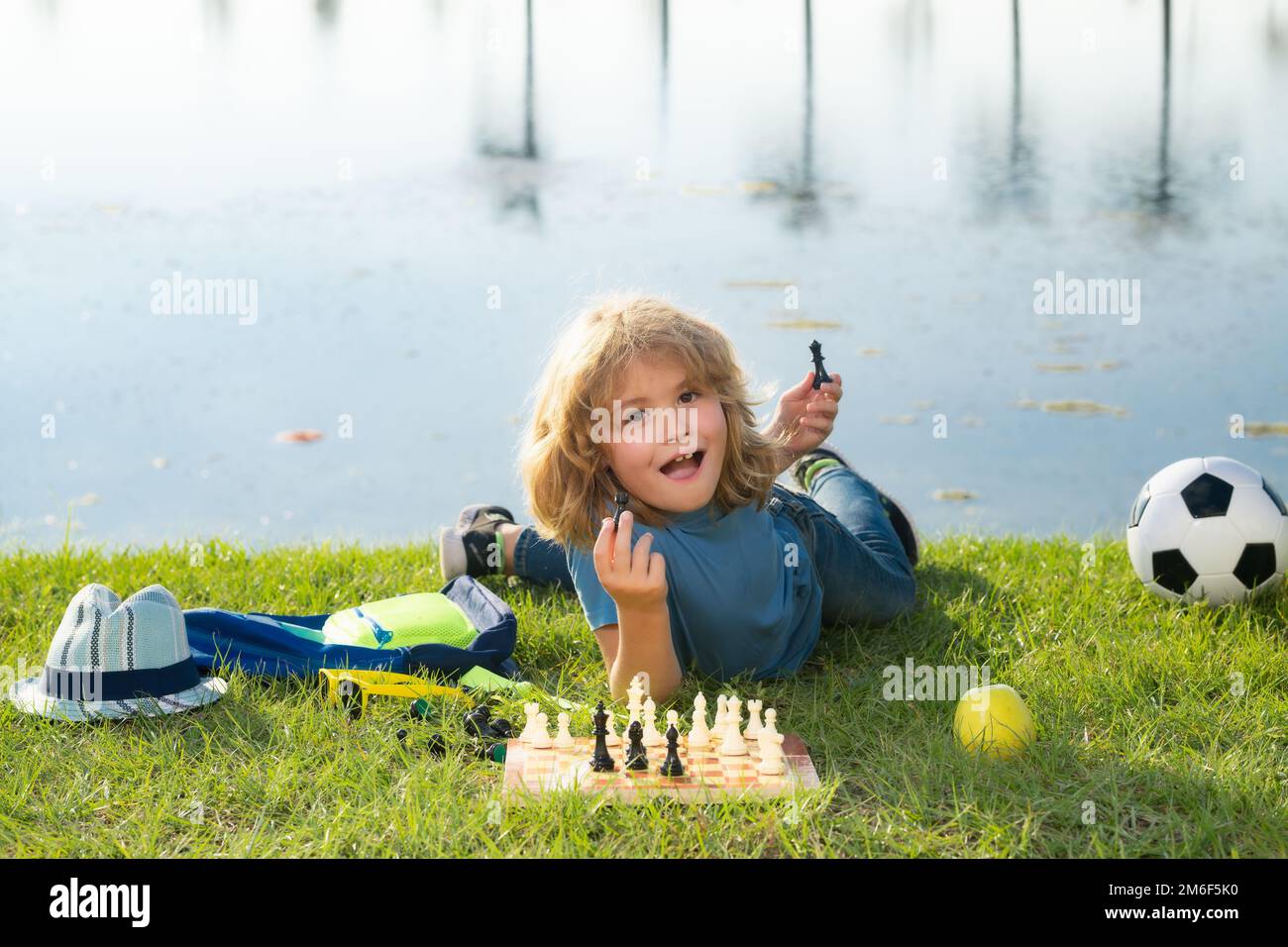 Der Junge zeigt Schachfiguren auf einem Schachbrett. Kleines Kind spielt Schach. Kind spielt Brettspiel. Denk-Kind-Brainstorming und Idee im Schachspiel. Schach Stockfoto