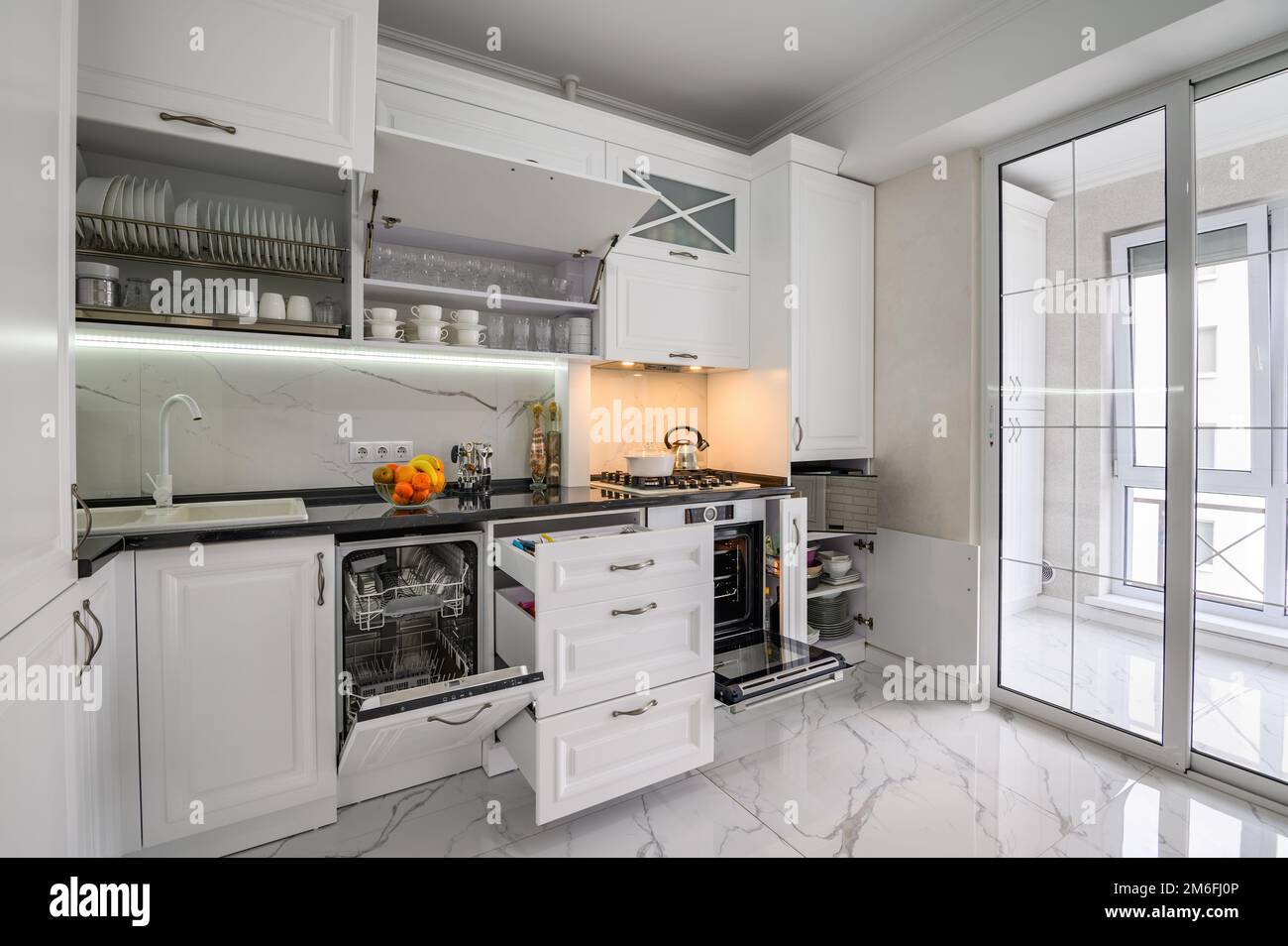 Luxuriöse weiße moderne Kücheneinrichtung, Schubladen herausgezogen, Tür des Geschirrspülers offen Stockfoto