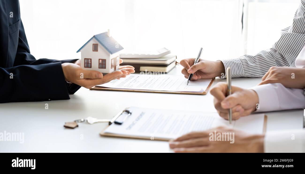 Immobilienmakler mit Paar, das einen Deal schließt und einen Vertrag unterzeichnet. Stockfoto
