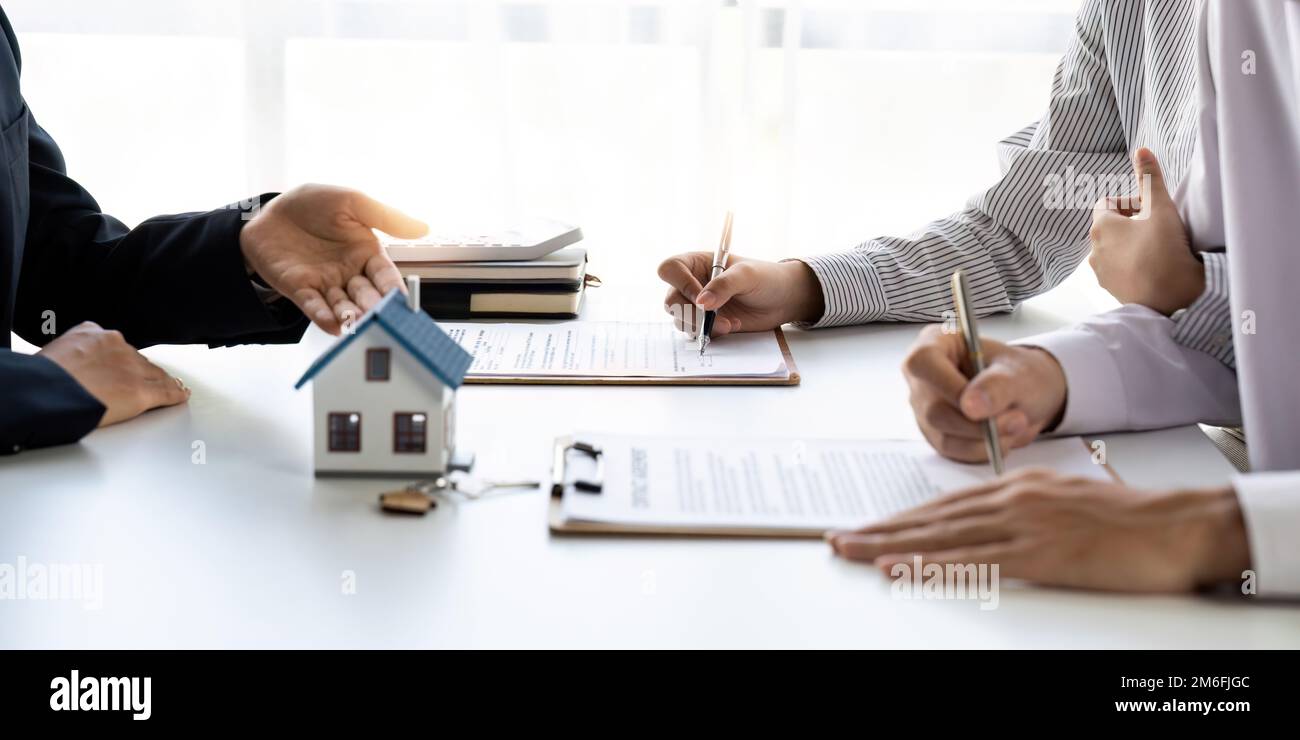 Immobilienmakler mit Paar, das einen Deal schließt und einen Vertrag unterzeichnet. Stockfoto