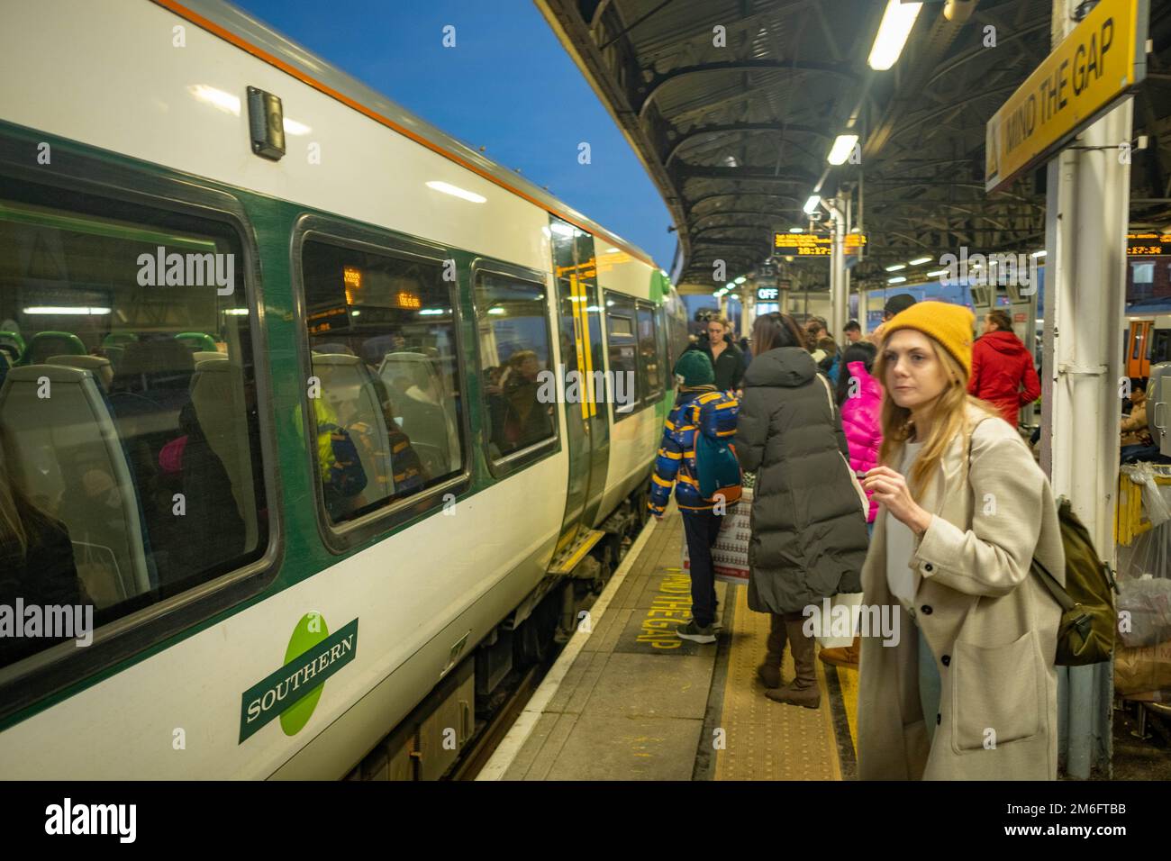 London - Dezember 2022: Passagiere auf dem Bahnsteig Clapham Junction steigen in einen Southern Train ein Stockfoto