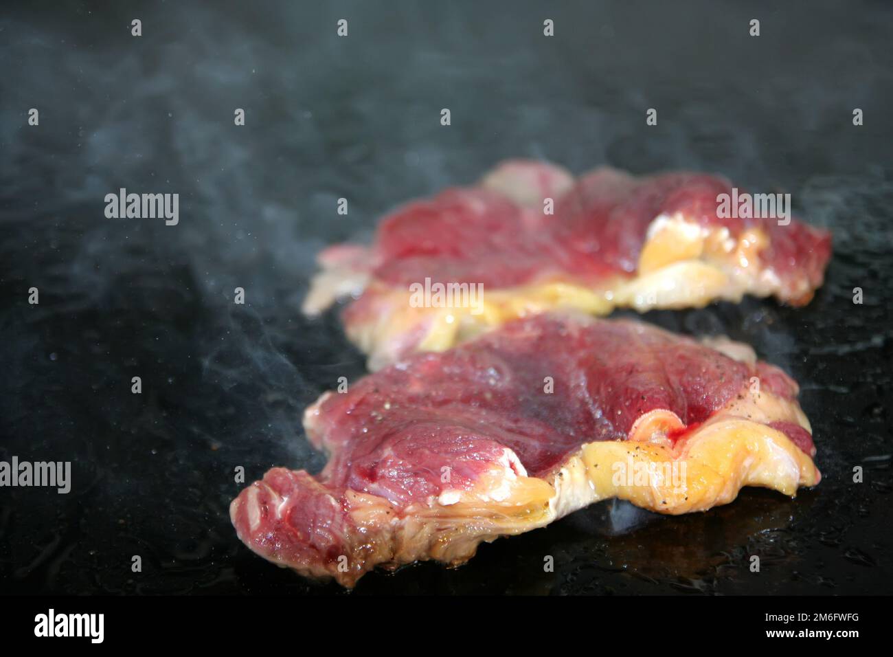 Geschnittenes Steak mit fettem Grillgut und weißem Rauch Stockfoto