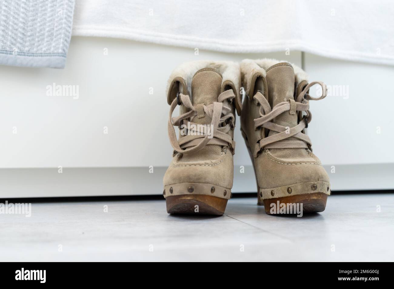 Beigefarbene Winterstiefel mit sehr hohen Absätzen vor einer weißen Garderobe. Hochwertiges Foto Stockfoto