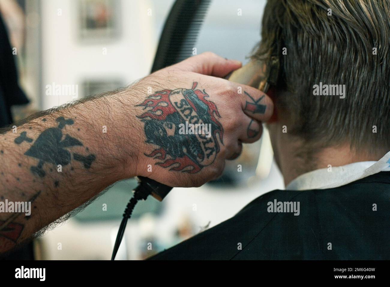 Der Friseur schneidet jungen Männern die Haare. Rückansicht eines Mannes, der im Friseursalon mit einer Haarschneidemaschine kurze Haare schneidet. Stockfoto