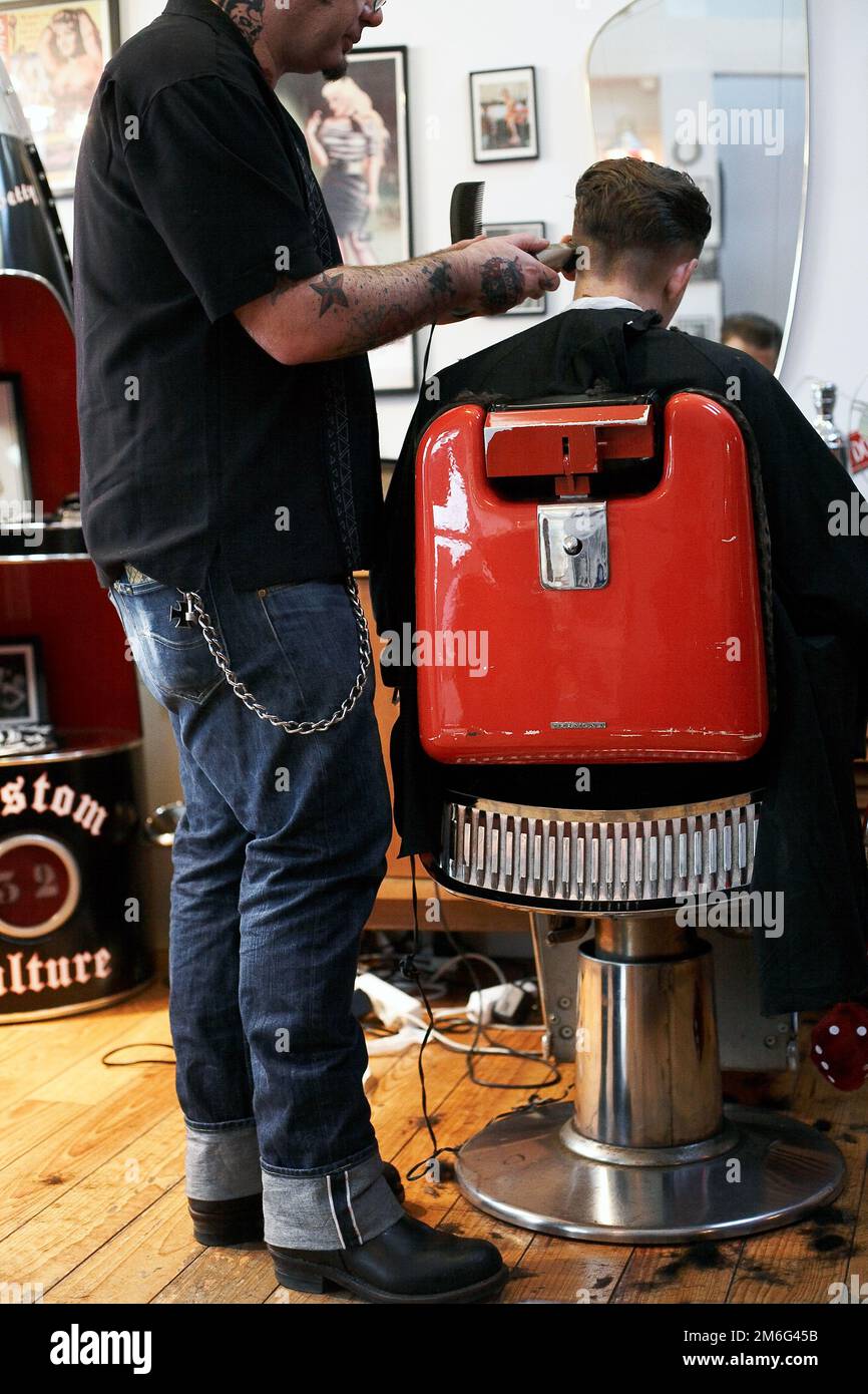 Der Friseur schneidet jungen Männern die Haare. Rückansicht eines Mannes, der im Friseursalon mit einer Haarschneidemaschine kurze Haare schneidet. Stockfoto