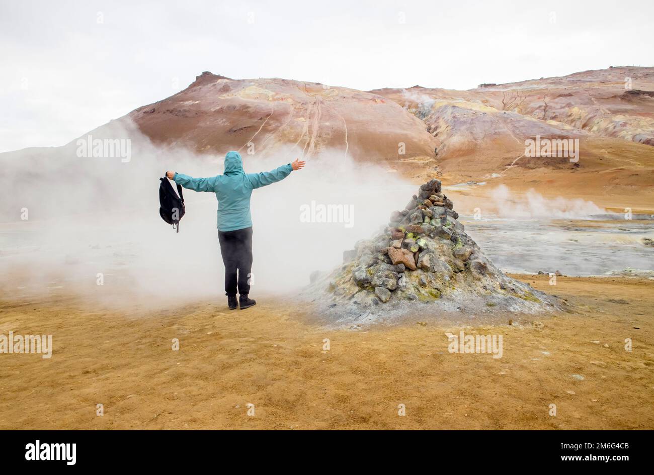 Frau Tourist in Hverir, isländische geothermische Gegend am Namafjall Vulkan Berg. Steht in einer natürlichen Dampfdüse in stinkendem Dampf. Stockfoto