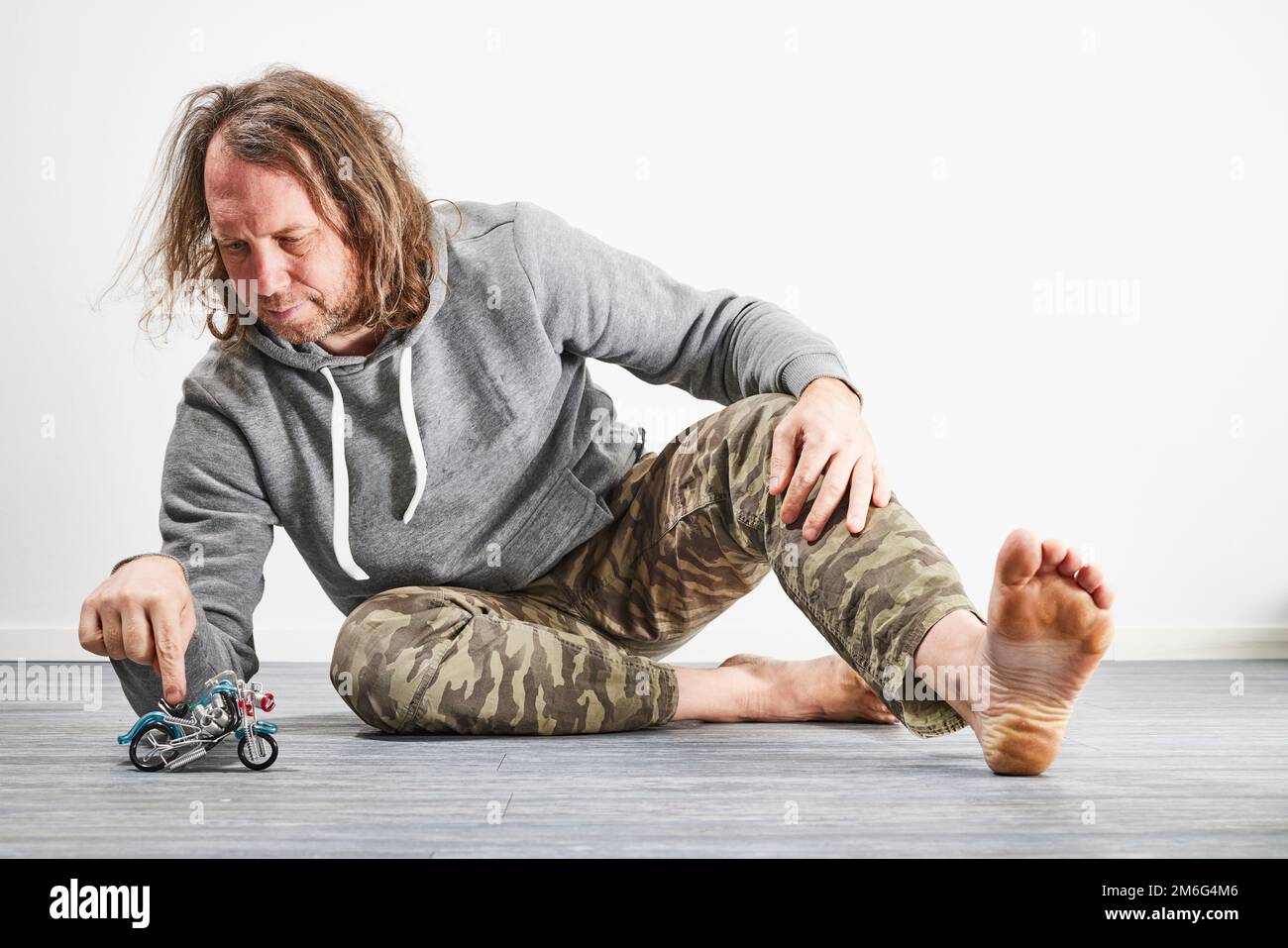 Dad spielt mit Spielzeugmotorrädern auf dem Boden Stockfoto