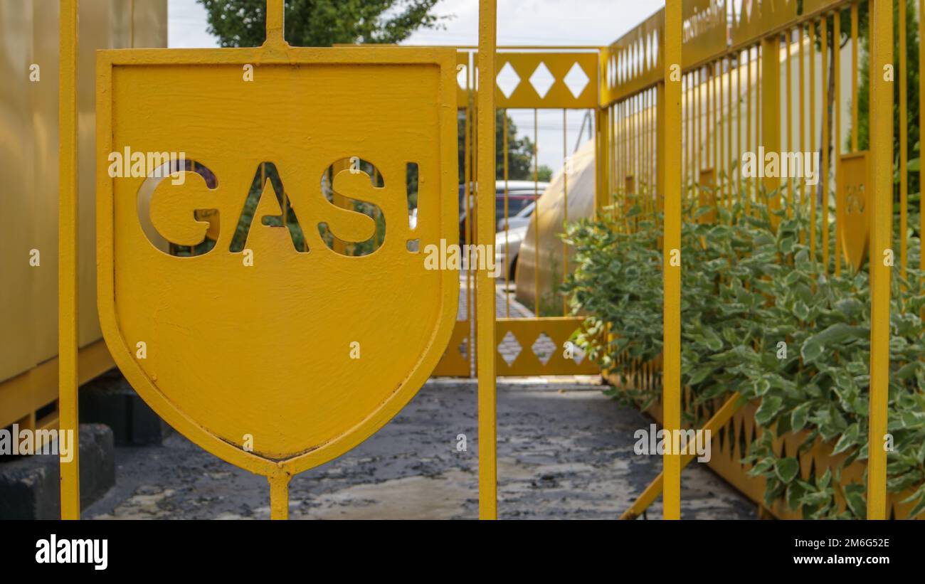 Warnung an einem Metallkäfig mit Gasausrüstung für die Öffentlichkeit. Achtung, Gasleitung. Die Inschrift in englischer GAZ. Eine gelbe Warnung Stockfoto