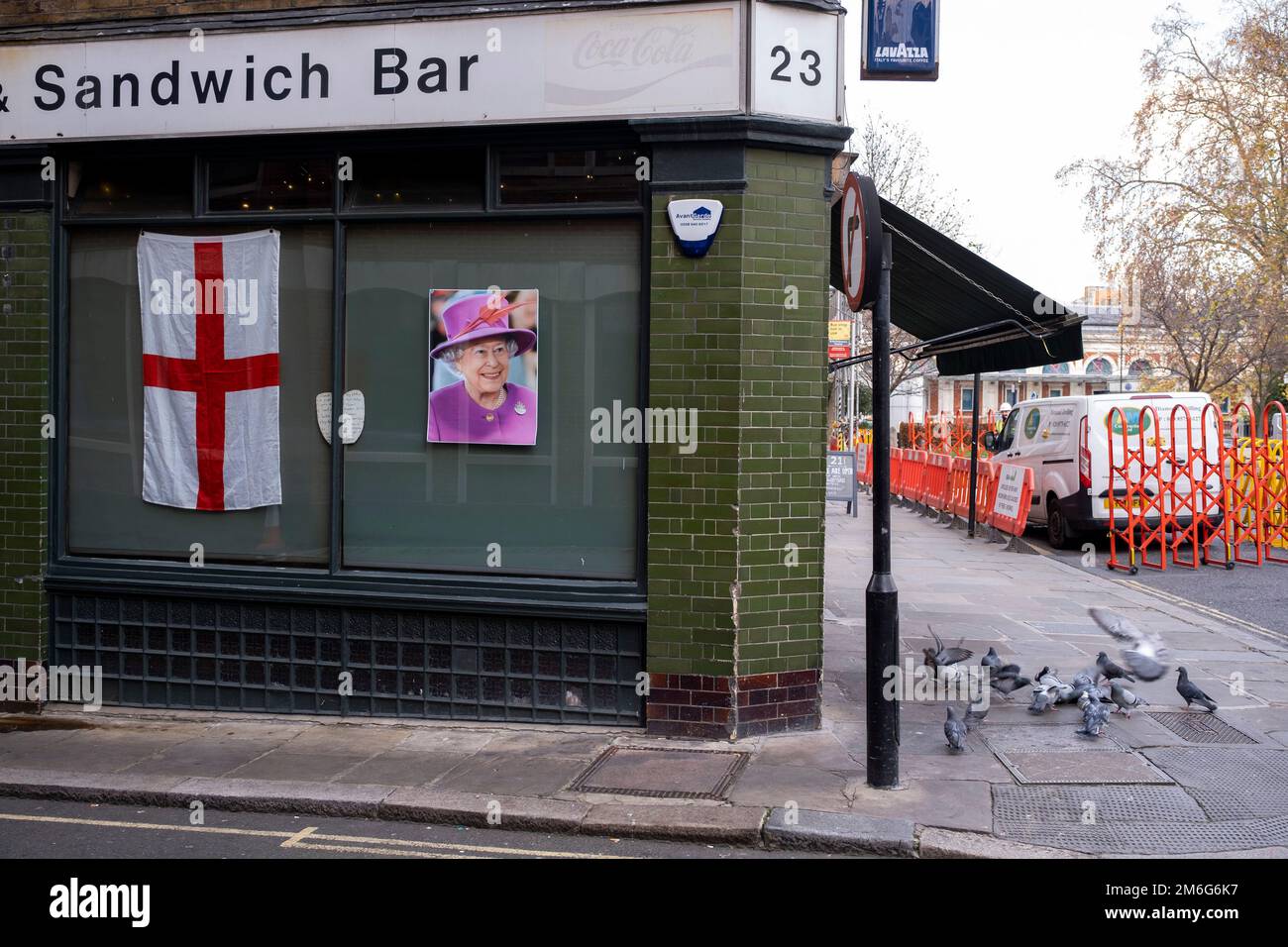 Gesicht von Königin Elisabeth II. Neben der Flagge des Saint Georges Cross in der Witwe einer Sandwich-Bar in Smithfields am 5. Dezember 2022 in London, Großbritannien. Stockfoto