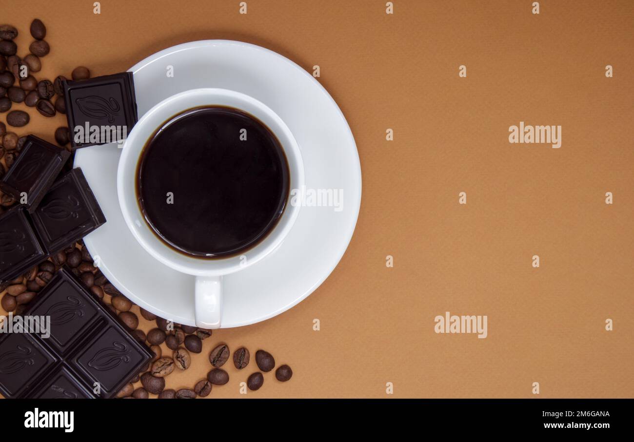 Schwarzer amerikanischer Kaffee ohne Milch in einer weißen Tasse, Schokolade und Kaffeebohnen. Draufsicht, flach liegend, für Text platzieren. Eine Tasse Aroma Stockfoto