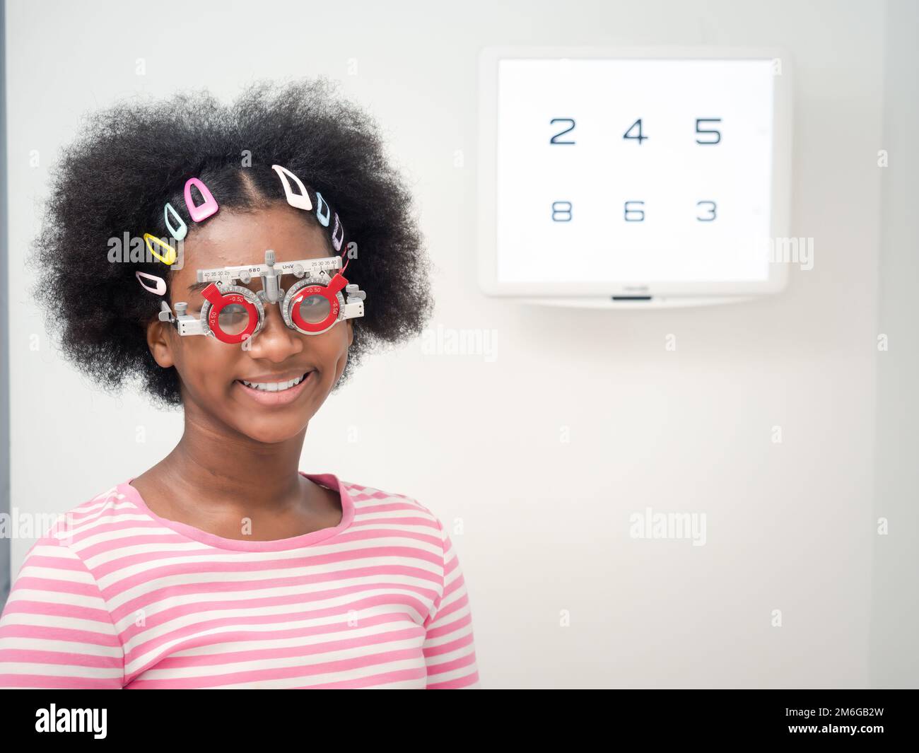 Afrikanisches Mädchen mit optischem Versuchsrahmen zur Bestimmung der Sehschärfe. Gesundheitsfürsorge, Medizin, Menschen, Sehvermögen und Technologiekonzept Stockfoto