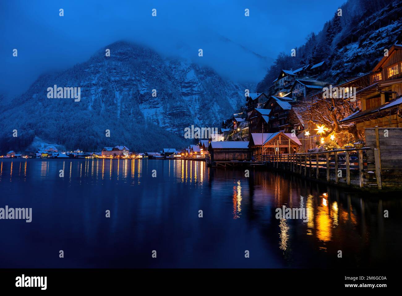 Wunderschönes Stadtbild der besonderen Stadt Hallstatt in Österreich Salzkammergut verschneite Winterberge und See nach Sonnenuntergang am Abend. Stockfoto