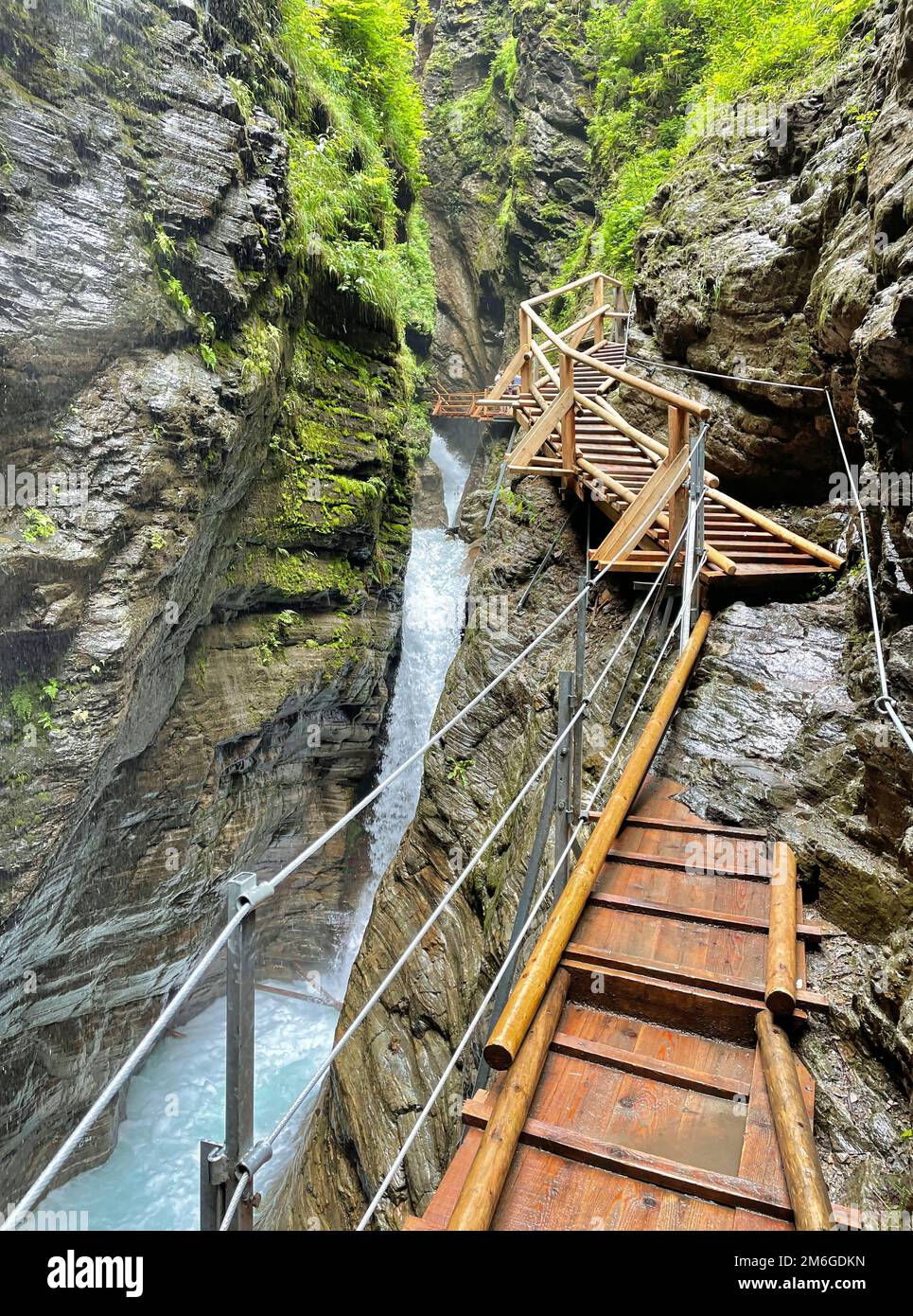 Hölzerner Fußweg als Brücke über rauschenden Wasserfall Stockfoto