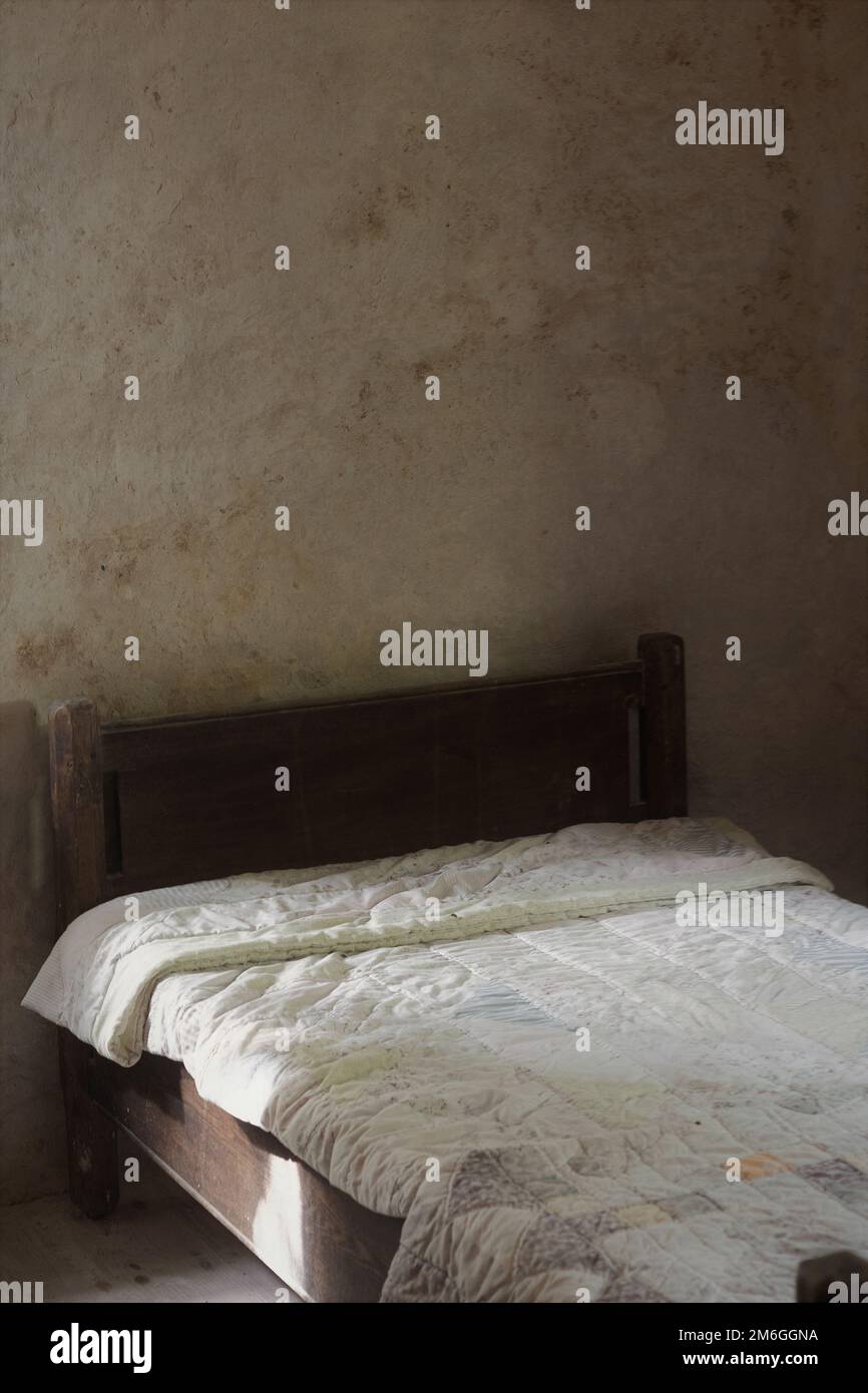 Ein altes Bett mit einem Holzrahmen und einer Steppdecke. Stockfoto