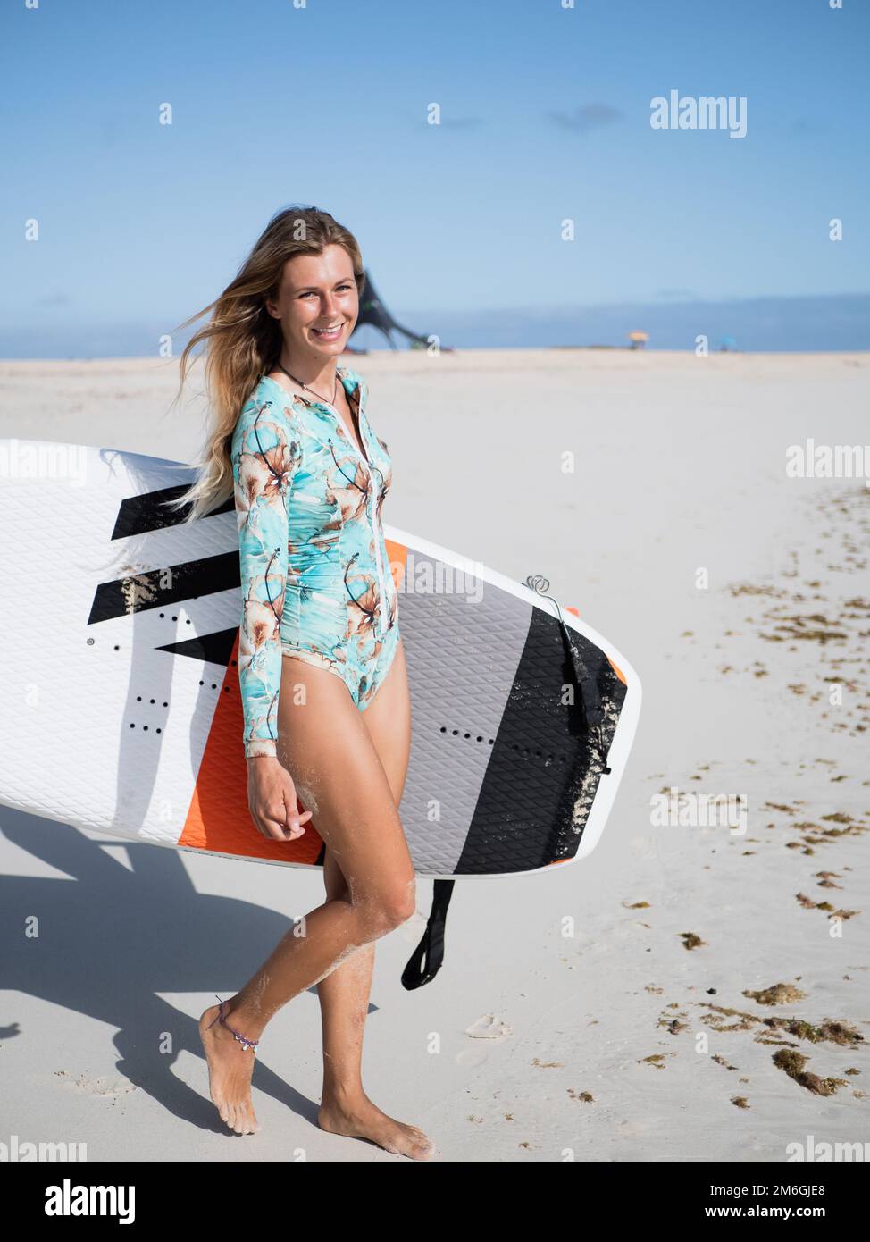 Junge, kaukasische Surferin mit Tragflächensurfbrett am Strand Stockfoto