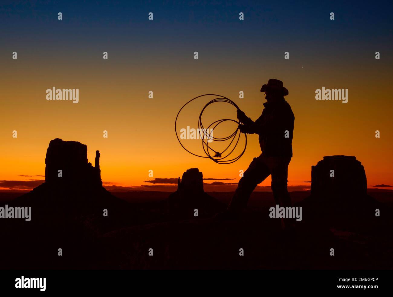 Eine Silhouettenaufnahme eines Cowboys mit einer Peitsche bei Sonnenaufgang Stockfoto
