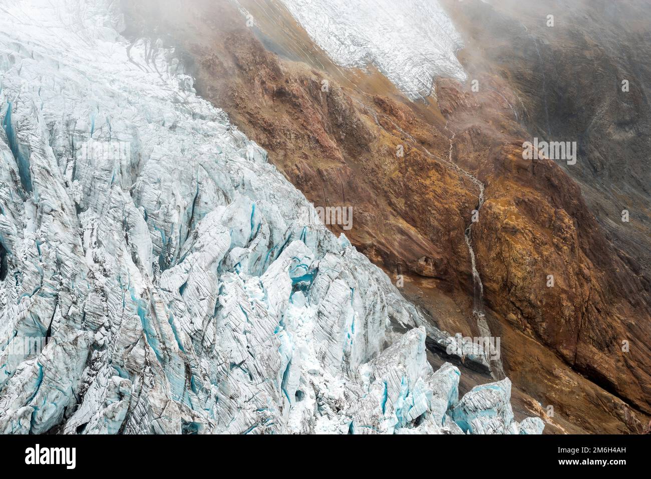 Gletscher des Vulkans Cayambe mit Wasserfall aus schmelzendem Wasser im Nebel, Anden, Ecuador. Stockfoto