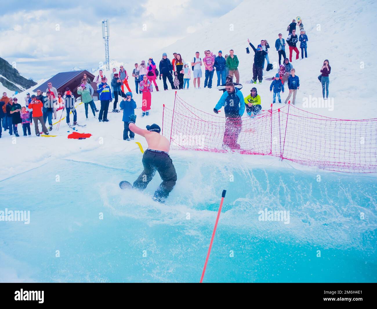 Russland, Sotschi 11.05.2019. Ein Mann ohne Oberbekleidung fährt auf dem Wasser mit einem Snowboard. Das Publikum beobachtet und fotografiert ihn Stockfoto