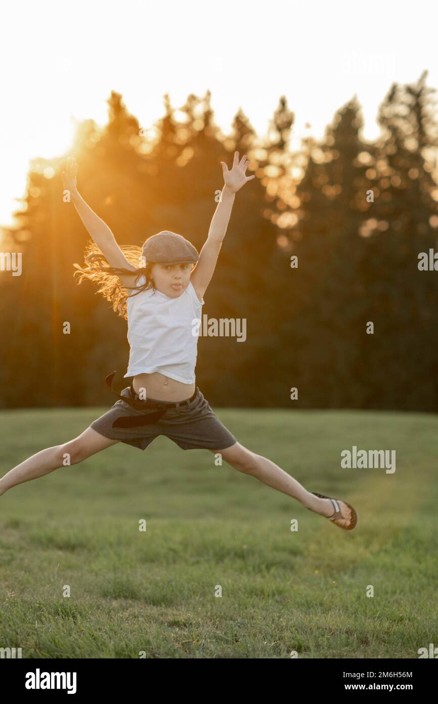 Mädchen, 8 Jahre, springt bei Sonnenuntergang auf einer Wiese Stockfoto