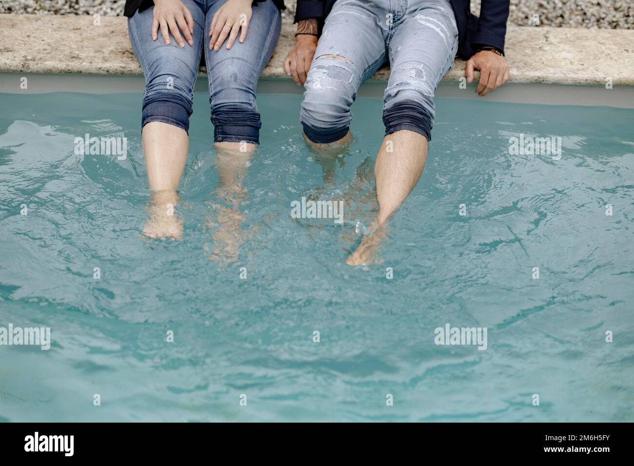 Vier Beine in Jeans im Swimmingpool Stockfoto