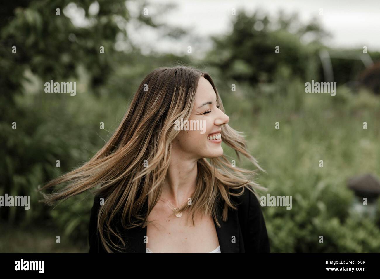 Lachende junge Frau im Porträt, 25, mit fliegenden Haaren Stockfoto
