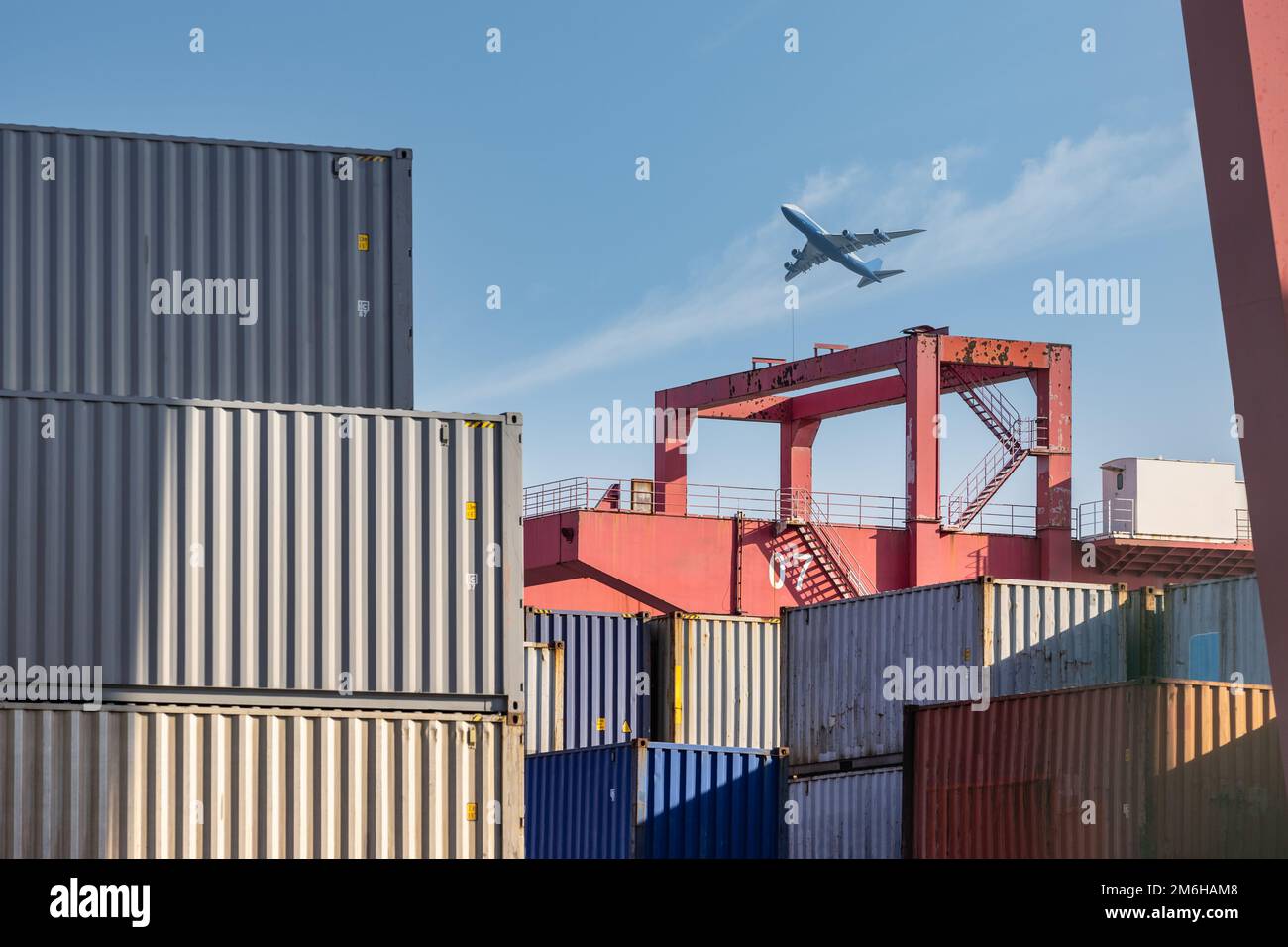 Containerhof-Nahaufnahme mit Flugzeug am Himmel Stockfoto