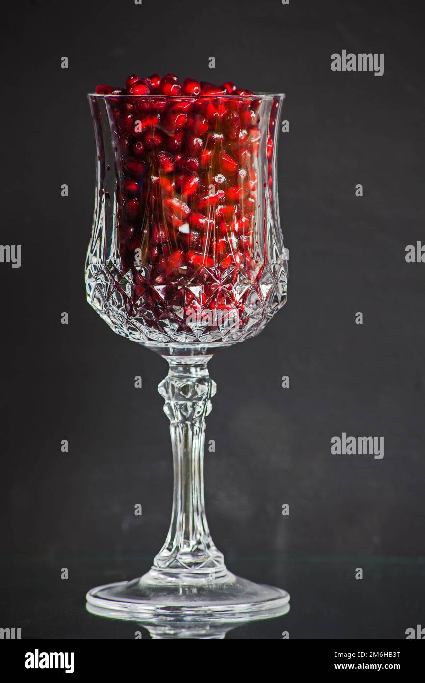 Noch lebend aus einem einschneidenden Kristallglas gefüllt mit glänzenden Granatapfelsamen. Stockfoto
