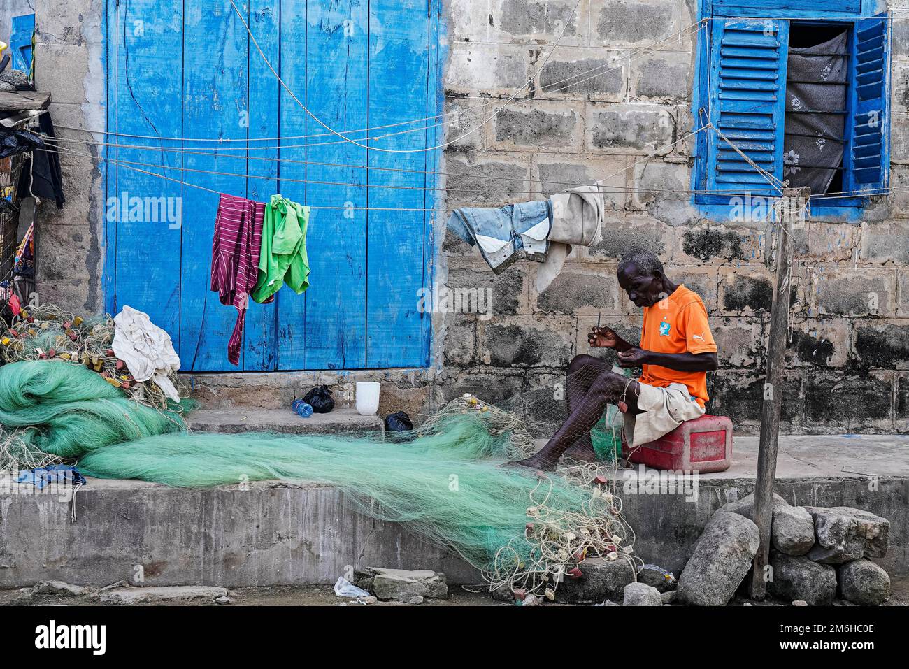 Ein Mann, der Netze vor seinem Haus repariert, Elmina, Golf von Guinea, Ghana Stockfoto