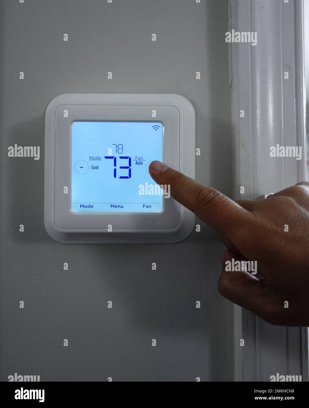 Person, die die Temperatur zu Hause mit einem intelligenten Thermostat einstellt Stockfoto