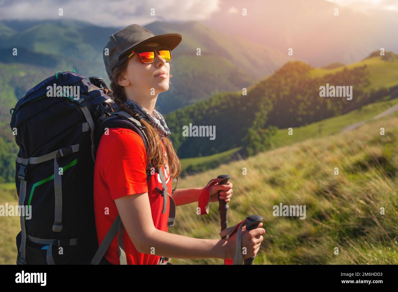 Ein touristisches Mädchen mit Rucksack bewundert den Sonnenuntergang vom Berg aus Stockfoto