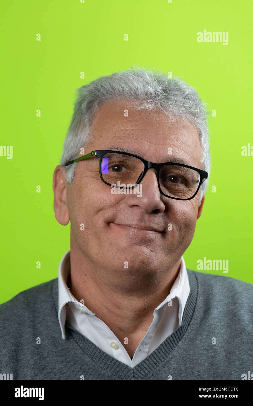 Porträt eines gutaussehenden weissen Seniorenmannes mit Brille, der in die Kamera schaut und mit isoliertem grünem Hintergrund lächelt. Selbstbewusster Geschäftsmann, ceo, Chef Fre Stockfoto