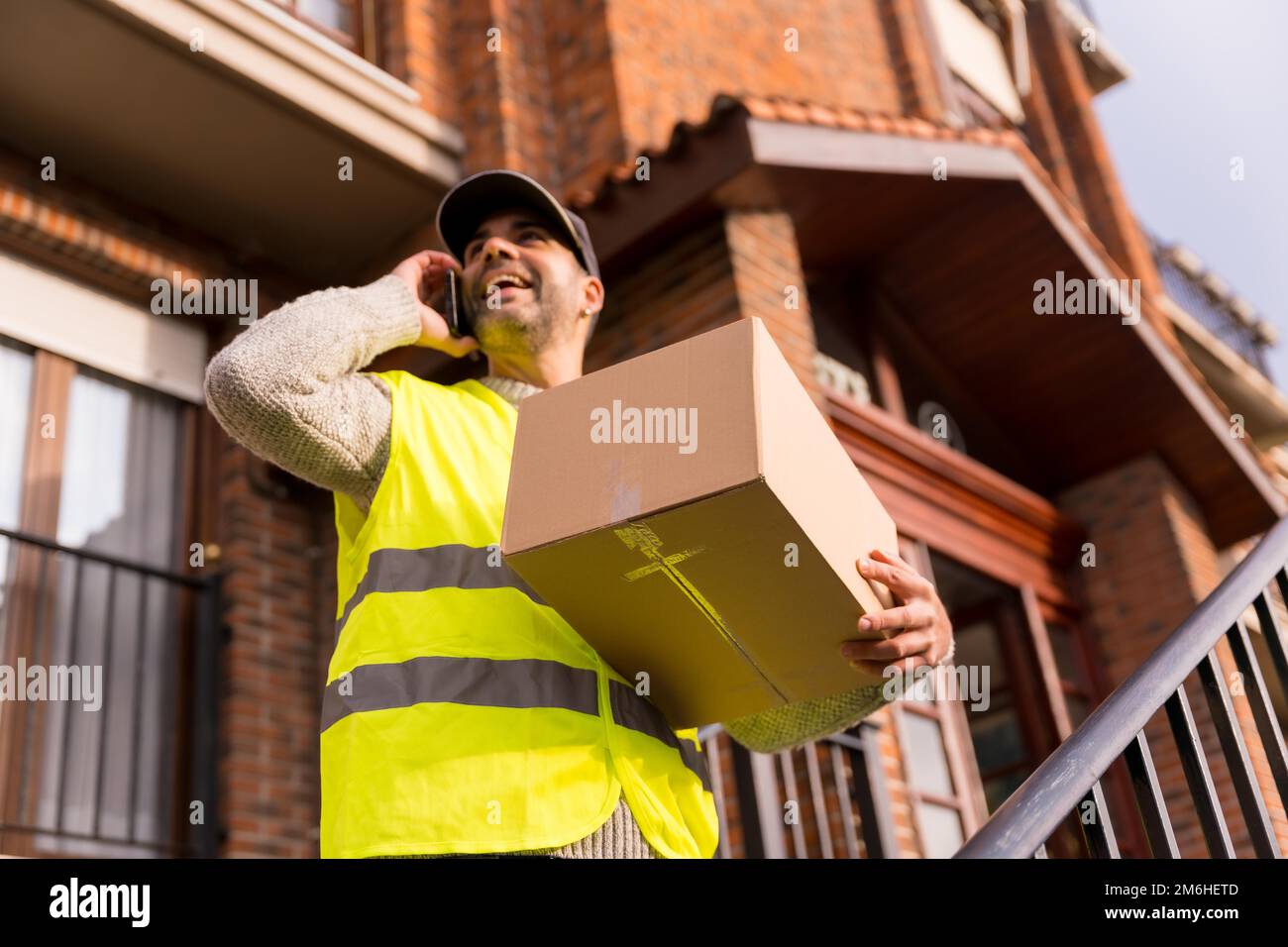 Der Paketzusteller eines Online-Shops, die Treppe des Hauses ruft den Kunden an Stockfoto
