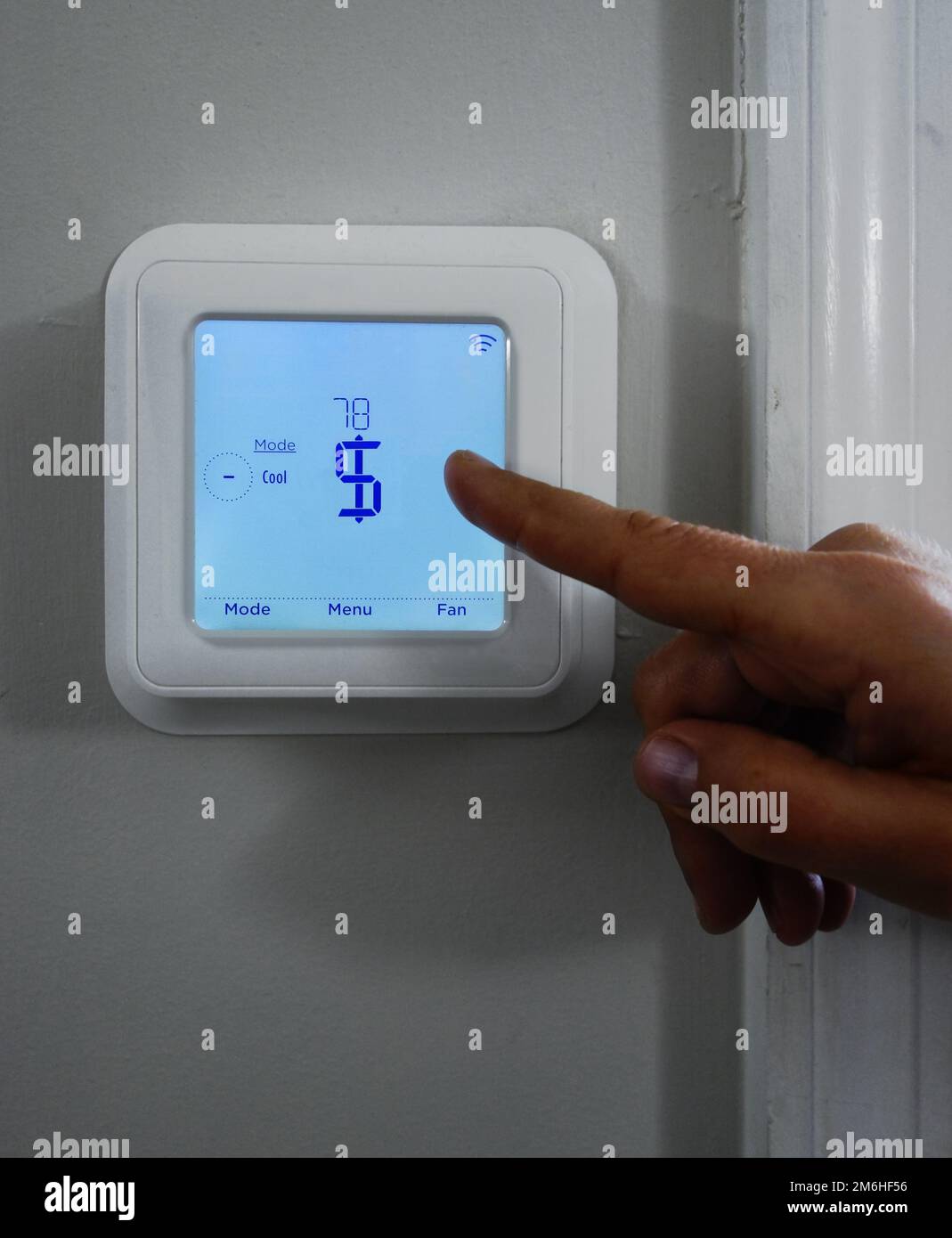Zeige mit dem Finger auf ein Dollarzeichen auf einem intelligenten Thermostat -- Kostenkonzept für Heizung und Kühlung Stockfoto