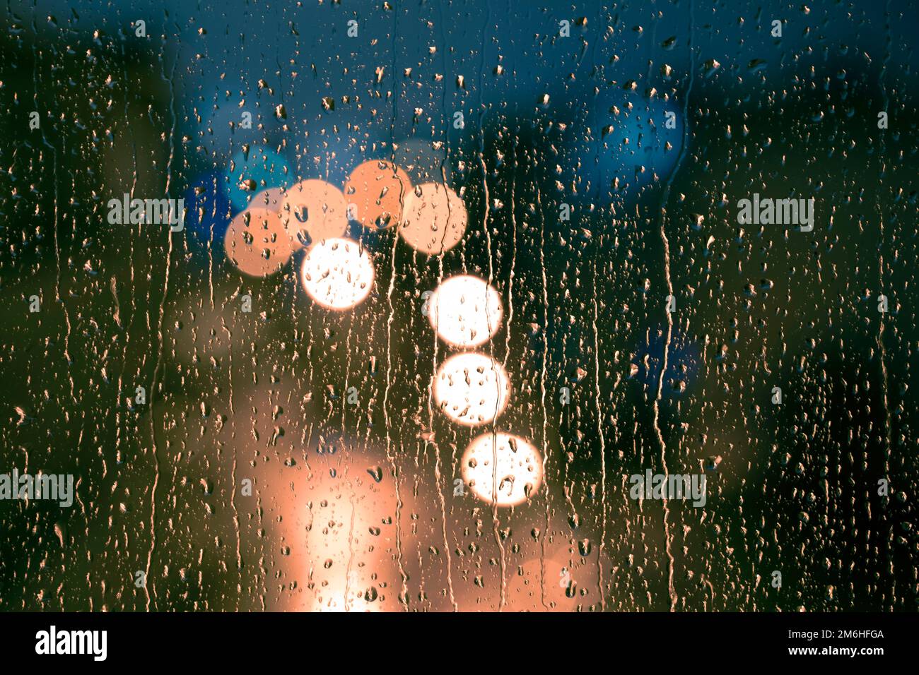 Wassertropfen auf die Scheibe, Glas. Die Lichter der Stadt. Bokeh - abstrakter, farbenfroher Hintergrund. Stockfoto