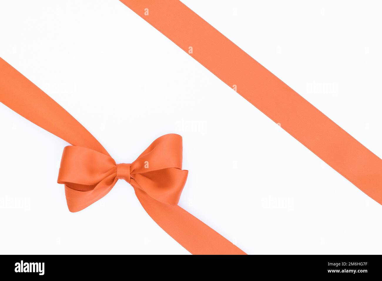 Schleife aus Satinband für Geschenkpaket in Orange, isoliert auf weißem Hintergrund. Hintergrund mit Schleife auf weißem Hintergrund. Stockfoto