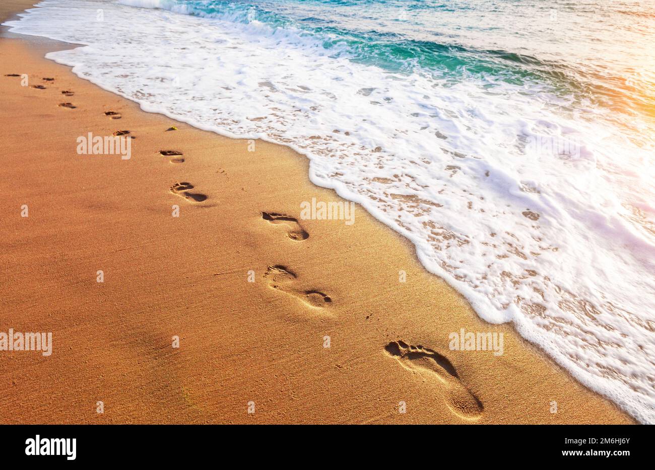Fußabdrücke am tropischen Strand und wunderschöne Wellen Stockfoto