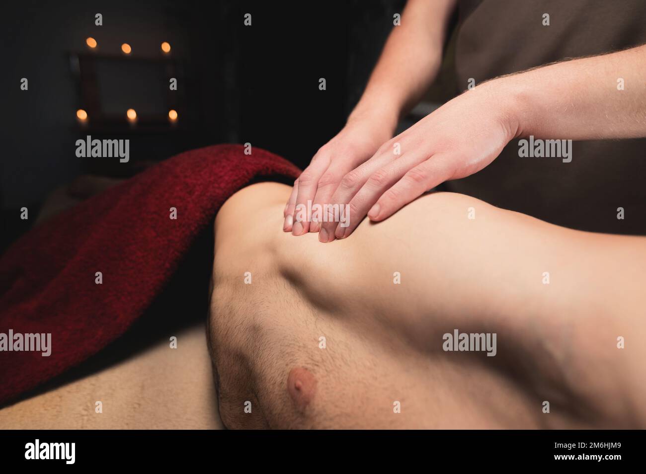 Professionelle männliche Sportmassage der Hüfte und des Knies in einem dunklen Massageraum. Premium-Massagen. Speicherplatz kopieren Stockfoto
