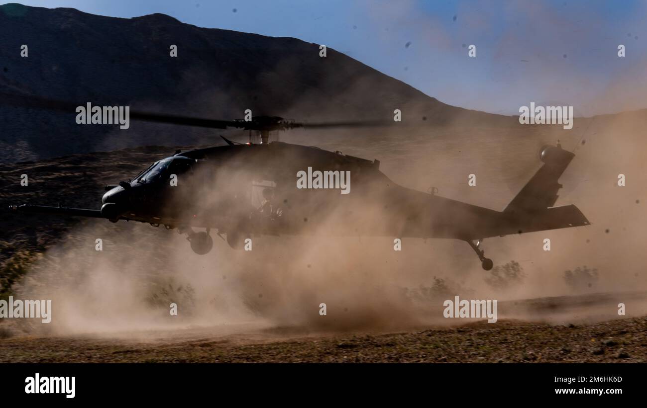 Ein HH-60G Pave Hawk Combat Search and Rescue (CSAR) Helikopter schweben über dem Boden, während Captain Garret Wells und 1. Lieutenant William Leshley, 66. Rescue Squadron, 28. April 2022 in North Las Vegas, Nevada, fliegen. Die Ausrüstung für die Mission PAVE Hawk umfasst eine einziehbare Betankungssonde während des Fluges, interne Kraftstofftanks, zwei von der Besatzung bediente Maschinen mit einem Kaliber von 7,62mm oder .50 sowie einen Frachthaken mit einem Fassungsvermögen von 8.000 kg (3.600 Pfund). Zur Verbesserung der Lufttransportfähigkeit und des Schiffsbetriebs sind alle HH-60Gs mit klappbaren Rotorblättern ausgestattet. Stockfoto