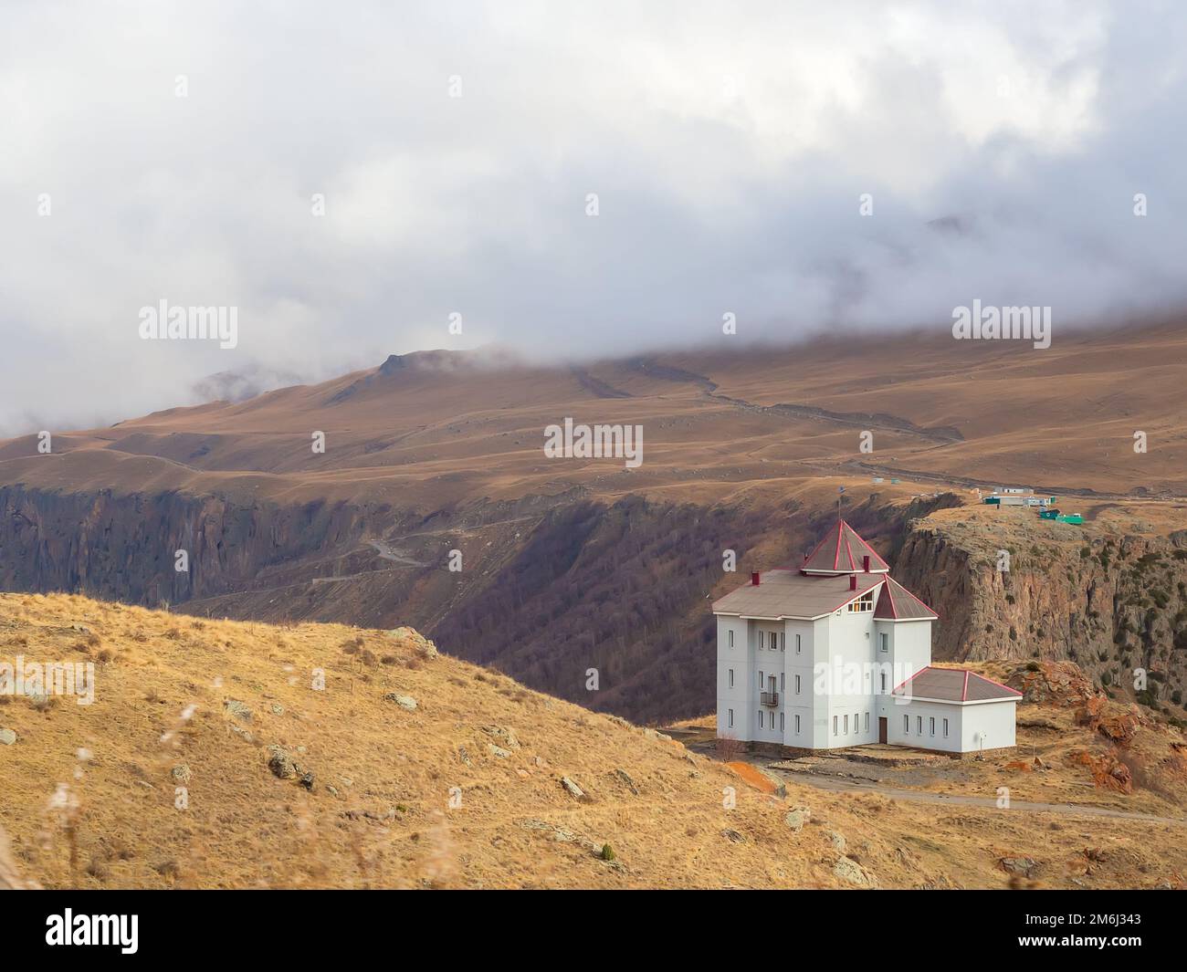 Das weiße Haus mit kleinen Fenstern steht hoch in den Bergen, wo der Nebel auf die Berggipfel fällt. Reise zur Hig Stockfoto