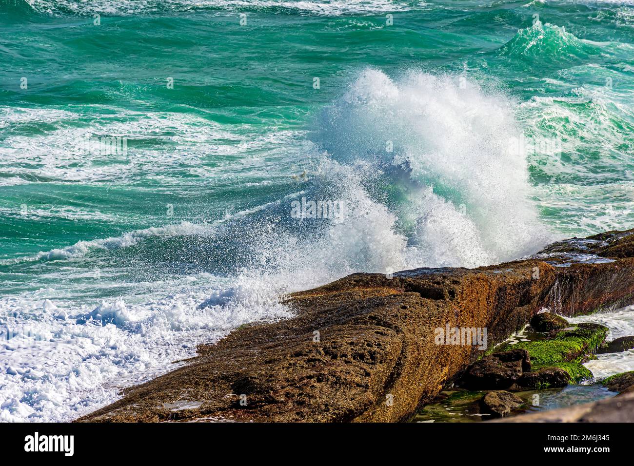 Welle bricht über Felsen und Wasser spritzt in die Luft Stockfoto