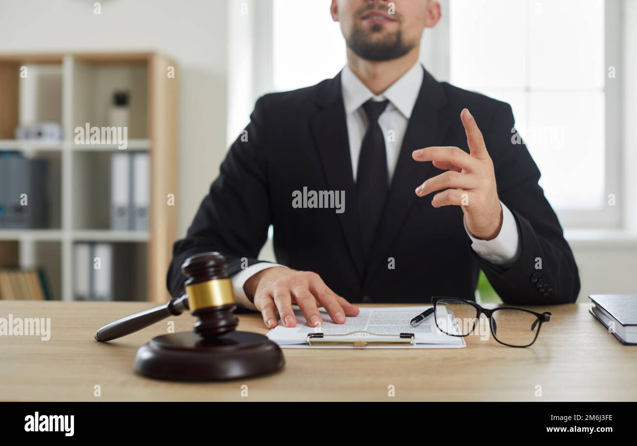 Rechtsanwalt, der professionelle Rechtsberatung leistet, während er mit Hammer am Büroschreibtisch sitzt Stockfoto