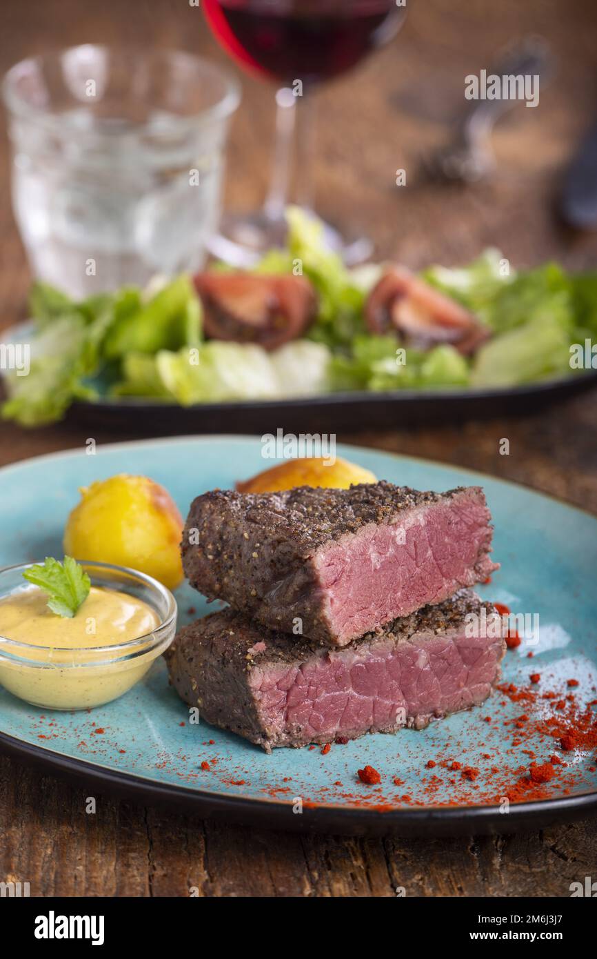 Steak-Scheiben auf blauem Teller Stockfoto