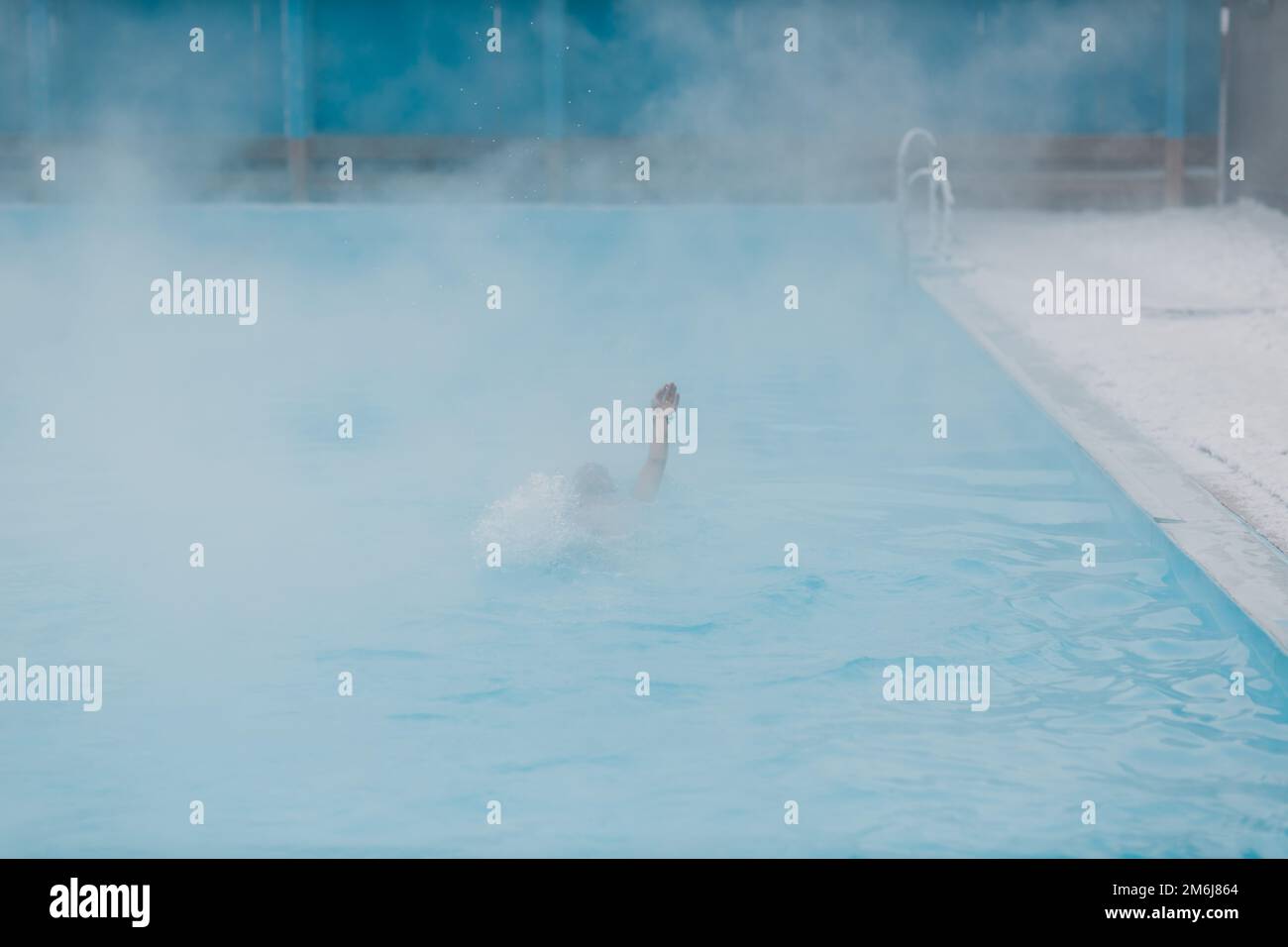 Fit Schwimmer männlichen Training schwimmen im offenen Winter Schwimmbad mit Nebel. Geothermisches Spa-Konzept im Freien. Stockfoto