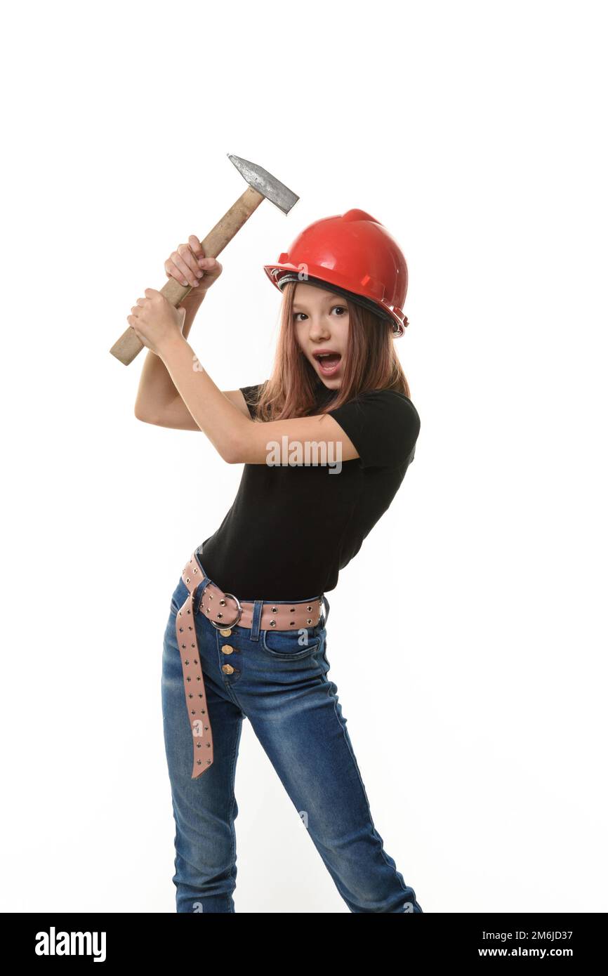 Ein Mädchen in einem harten Hut trifft sich mit einem Hammer auf den Kopf, Überraschung im Gesicht Stockfoto