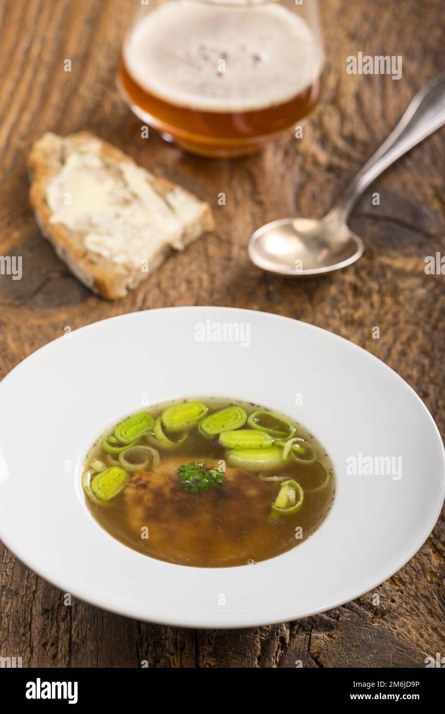 Österreichische Käseklößchen-Suppe auf Holz Stockfoto