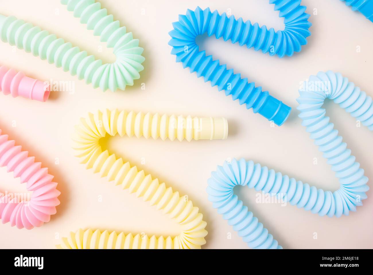 Trendige Spielzeuge für Kinder Pastelltöne farbenfrohe Pop-Tube auf beigefarbenem Hintergrund. Set aus Formen und Farben Wellrohr und Anti-Stress, Relax Stockfoto