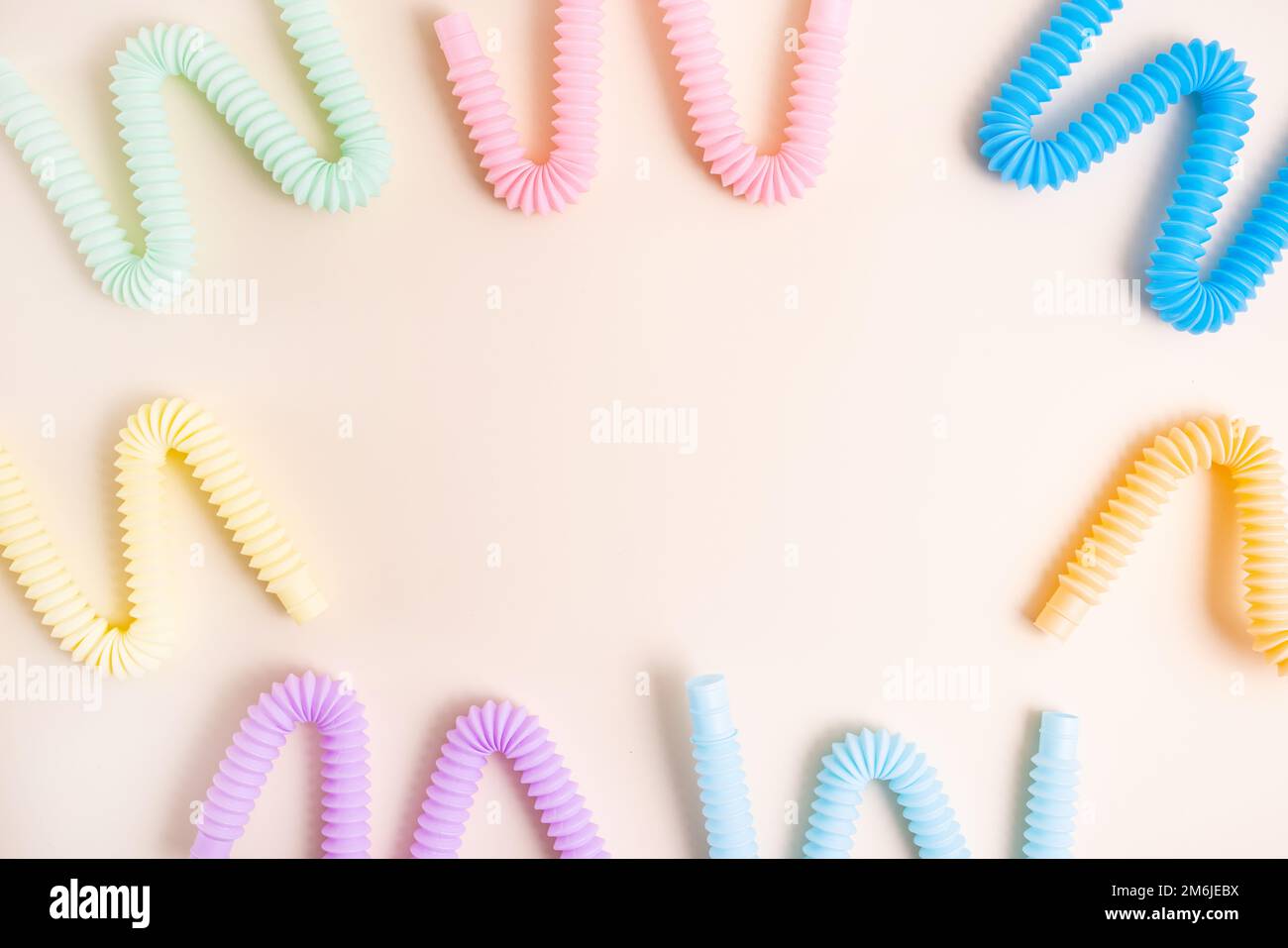 Trendige Spielzeuge für Kinder Pastelltöne farbenfrohe Pop-Tube auf beigefarbenem Hintergrund. Set aus Formen und Farben Wellrohr und Anti-Stress, Relax Stockfoto